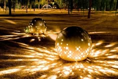 two large balls sitting in the middle of a park with trees and grass behind them