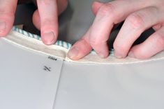 two hands on top of a piece of fabric with one hand over the edge of an open book