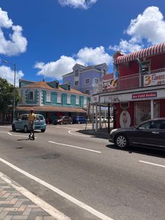 a man riding a bike down the middle of a street next to parked cars and buildings