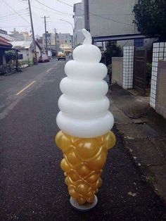 an ice cream cone is on the side of the road with balloons attached to it