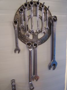 a bunch of wrenches hanging on a wall with some screwdrives attached to it