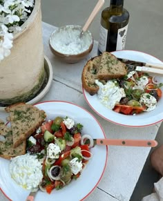 there are two plates with food on them next to a bottle of wine and some bread