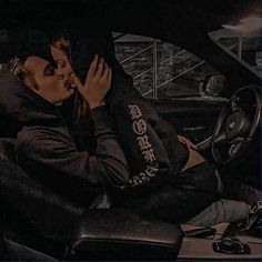 a man and woman are kissing in the back seat of a car while sitting next to each other