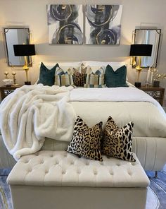 a white bed with pillows and blankets on top of it next to two framed pictures