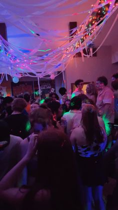 a group of people standing around in a room with streamers hanging from the ceiling