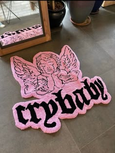 two pink rugs with black letters and angel wings on the floor in front of a mirror