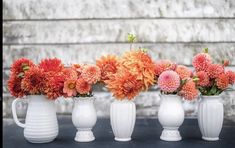 four white vases with flowers in them on a table