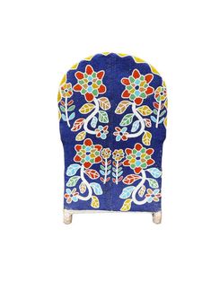 a blue chair with colorful flowers and leaves on it's back, against a white background