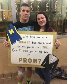 two people standing next to each other holding a sign