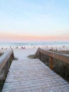 a wooden walkway leading to the beach at sunset