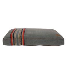 a dog bed that is made out of gray and red striped fabric with a brown stripe on the bottom