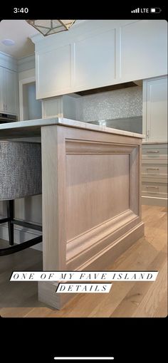 an island in the middle of a kitchen with white cabinets and wood flooring on it