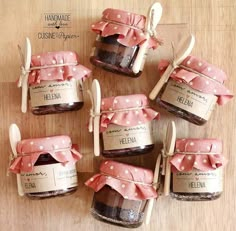 six jars with spoons and labels on them sitting on top of a wooden table