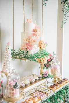 a table topped with lots of cakes and cupcakes next to a cake stand