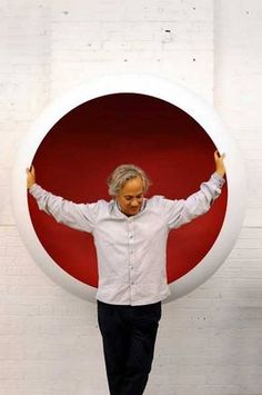 a man is standing in front of a red and white circle with his hands up