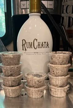 a bunch of cups sitting on top of a counter next to a bottle and some spoons