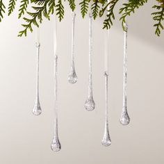 three silver spoons hanging from a christmas tree with green leaves on the top and bottom