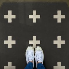 a person standing in front of a black and white floor with crosses painted on it