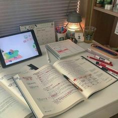 an open book sitting on top of a desk next to a computer monitor and pen