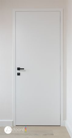 an empty room with a white door and black handles