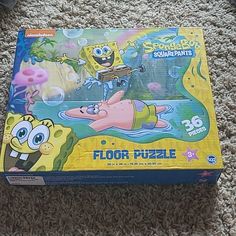 the spongebob squarepants floor puzzle is laying on the carpet next to an open box