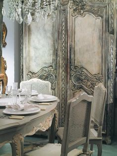 an ornately decorated table and chairs in front of a wall with peeling paint on it