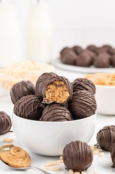 chocolate covered peanut butter balls in a white bowl next to other desserts and milk