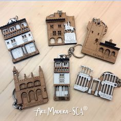 six wooden keychains with buildings on them sitting on top of a wood table