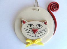 a ceramic ornament with a cat's face and yellow bow on it