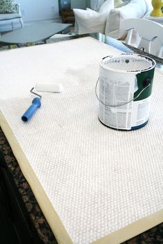 a can of paint sitting on top of a table next to a brush and roller