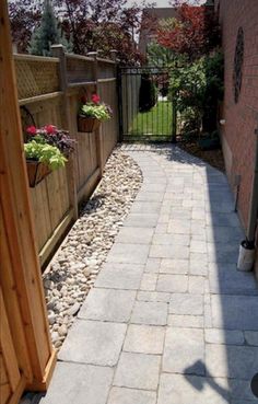 a long narrow brick walkway with flower boxes on each side and an iron gate at the end