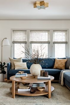 a living room with a blue couch and coffee table in front of two large windows