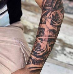 a man with a cross and roses tattoo on his arm