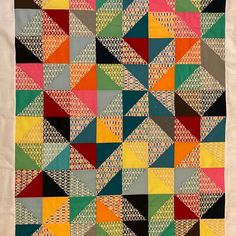 a multicolored quilt is hanging on the wall