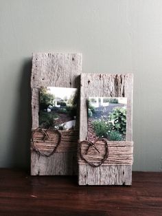 two wooden frames with hearts tied to them sitting on a table next to each other