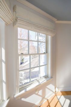 the sun shines through two windows in an empty room with white walls and wood floors