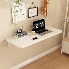 a laptop computer sitting on top of a white desk next to a clock and other items