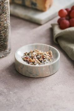 a bowl filled with granola sitting on top of a table next to some grapes