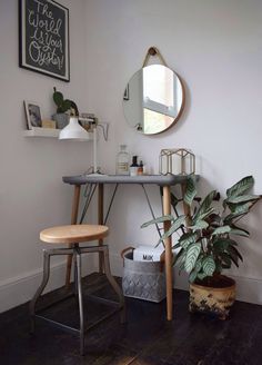 a bathroom with a mirror, stool and potted plant