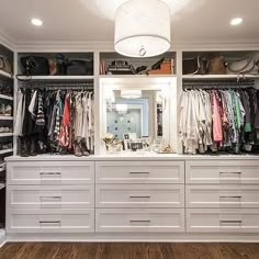 a walk in closet filled with lots of white drawers and clothes on top of shelves