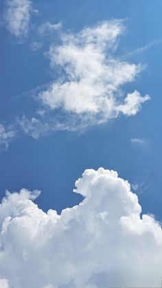 the airplane is flying high in the blue sky with white clouds above it and below