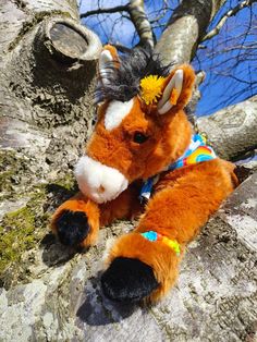 a stuffed horse sitting on top of a tree branch