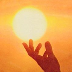 a person holding their hand up to the sun