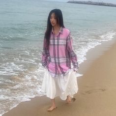 a woman standing on top of a beach next to the ocean