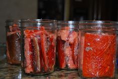 four jars filled with pickles sitting on top of a counter