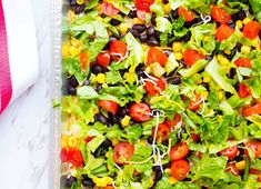 a salad with black beans, tomatoes, corn and lettuce