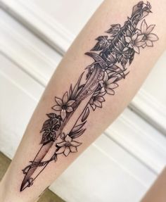 a tattoo on the leg of a woman with flowers and a knife in it's center