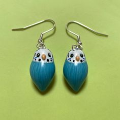 a pair of blue and white earrings with black dots on them sitting on a green surface