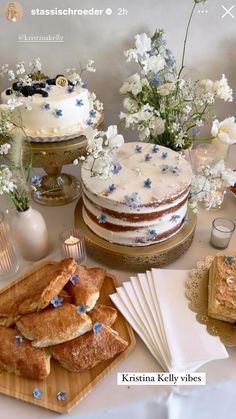 a table topped with cakes and desserts on top of wooden cutting boards next to flowers