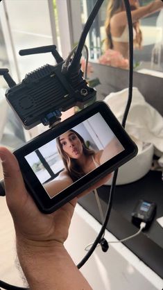 a person holding up a video camera to take a picture in front of a mirror